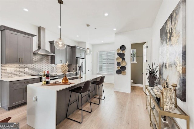 701 Pryor St SW # 5, Atlanta, GA 30315 - kitchen with wall chimney exhaust hood, appliances with stainless steel finishes, light countertops, a kitchen island with sink, and tasteful backsplash