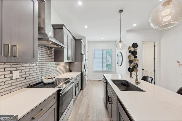 701 Pryor St SW # 5, Atlanta, GA 30315 - kitchen with stainless steel appliances, a sink, wall chimney exhaust hood, light wood-style floors, and light countertops