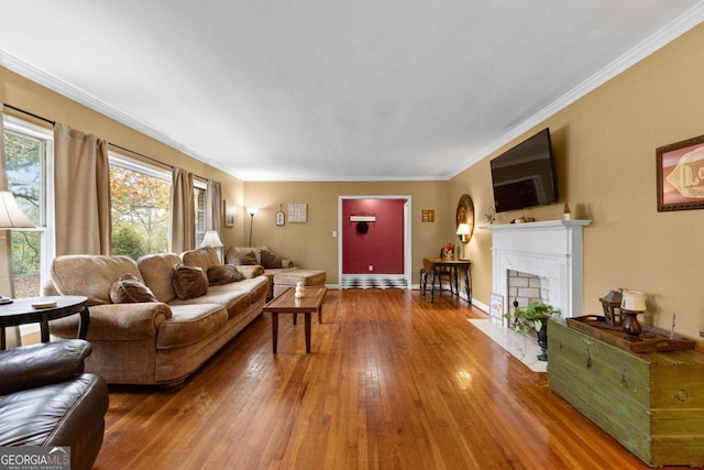 living area featuring hardwood / wood-style flooring, a fireplace with flush hearth, ornamental molding, and baseboards