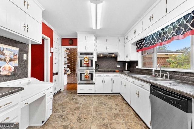 kitchen featuring stainless steel appliances, a sink, white cabinetry, dark countertops, and crown molding