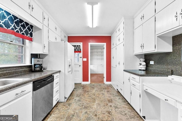 kitchen featuring stainless steel dishwasher, dark countertops, white cabinetry, ornamental molding, and stone finish floors