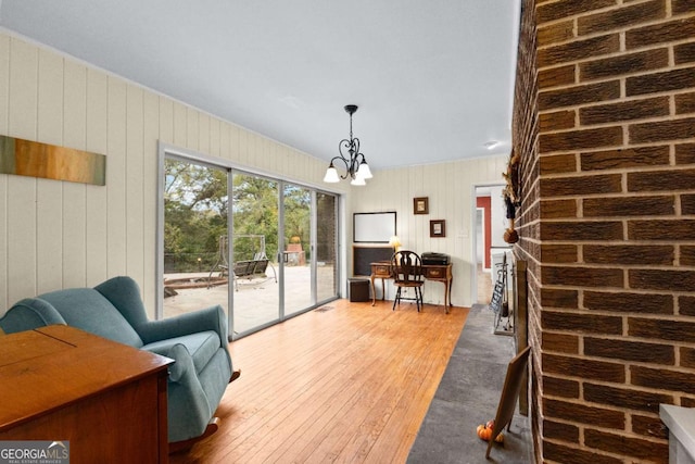 living area with wood-type flooring, a chandelier, wooden walls, and a fireplace
