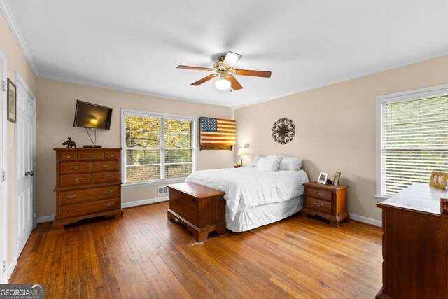 bedroom with crown molding, wood-type flooring, baseboards, and ceiling fan