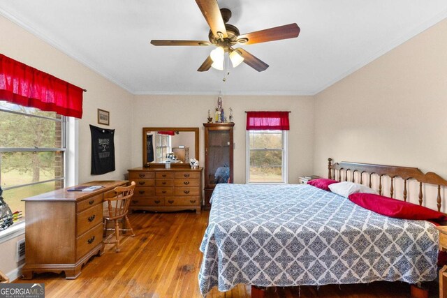 bedroom featuring hardwood / wood-style flooring, ornamental molding, and ceiling fan