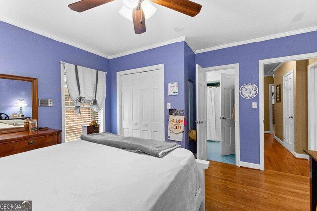 bedroom with wood finished floors, crown molding, baseboards, a closet, and a ceiling fan