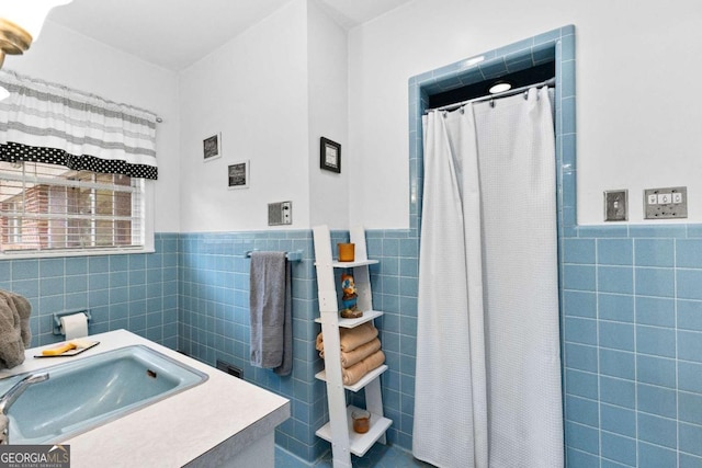 full bathroom featuring tile walls, a wainscoted wall, a sink, and curtained shower