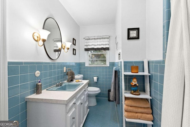 full bathroom featuring tile walls, wainscoting, toilet, vanity, and tile patterned floors