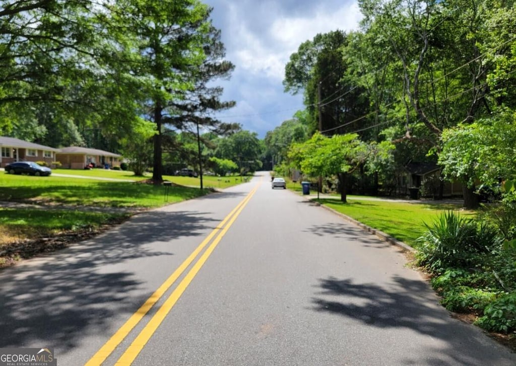 view of asphalt street with view of scattered trees