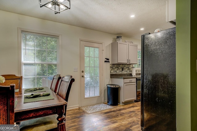 kitchen featuring black appliances, wood finished floors, dark countertops, decorative backsplash, and recessed lighting