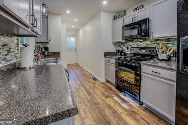 kitchen with black appliances, a sink, dark countertops, tasteful backsplash, and recessed lighting