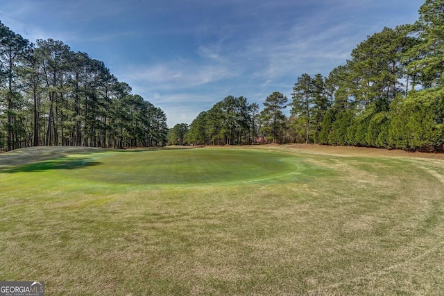 view of home's community with golf course view, a lawn, and view of scattered trees