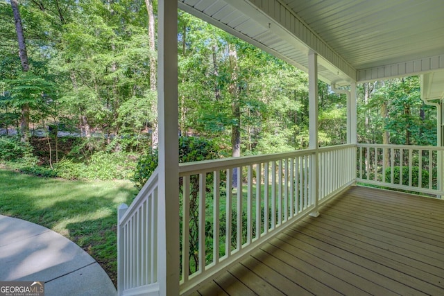 wooden deck with covered porch and a view of trees