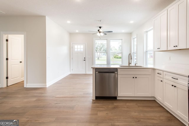 kitchen featuring a sink, stainless steel dishwasher, a peninsula, ceiling fan, and white cabinets