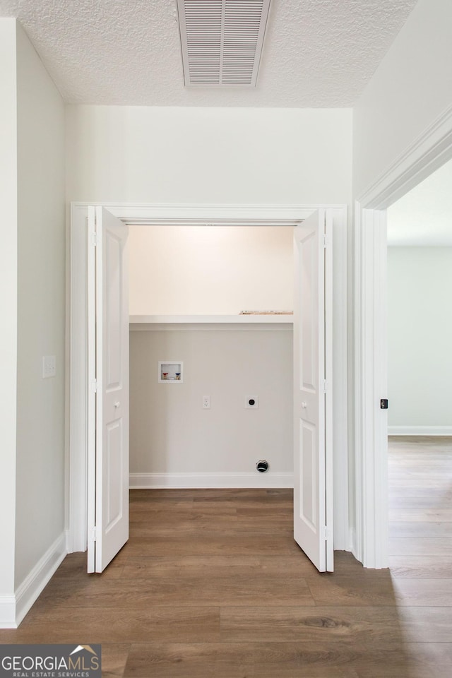 laundry room with washer hookup, hookup for an electric dryer, wood finished floors, a textured ceiling, and baseboards