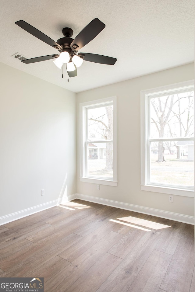 empty room featuring wood finished floors, baseboards, and ceiling fan