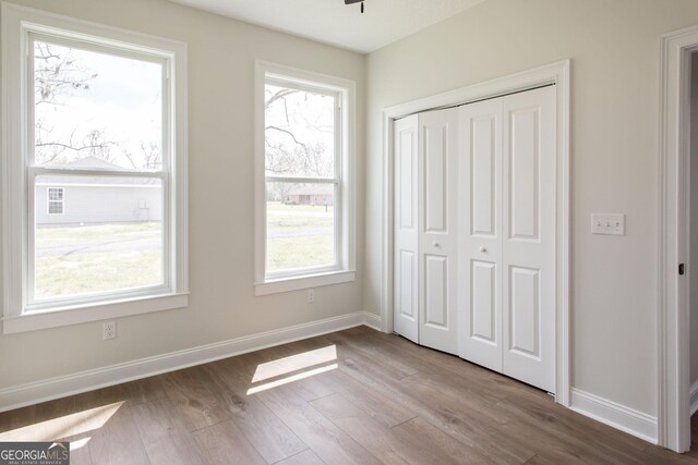 unfurnished bedroom with wood finished floors, a closet, and baseboards