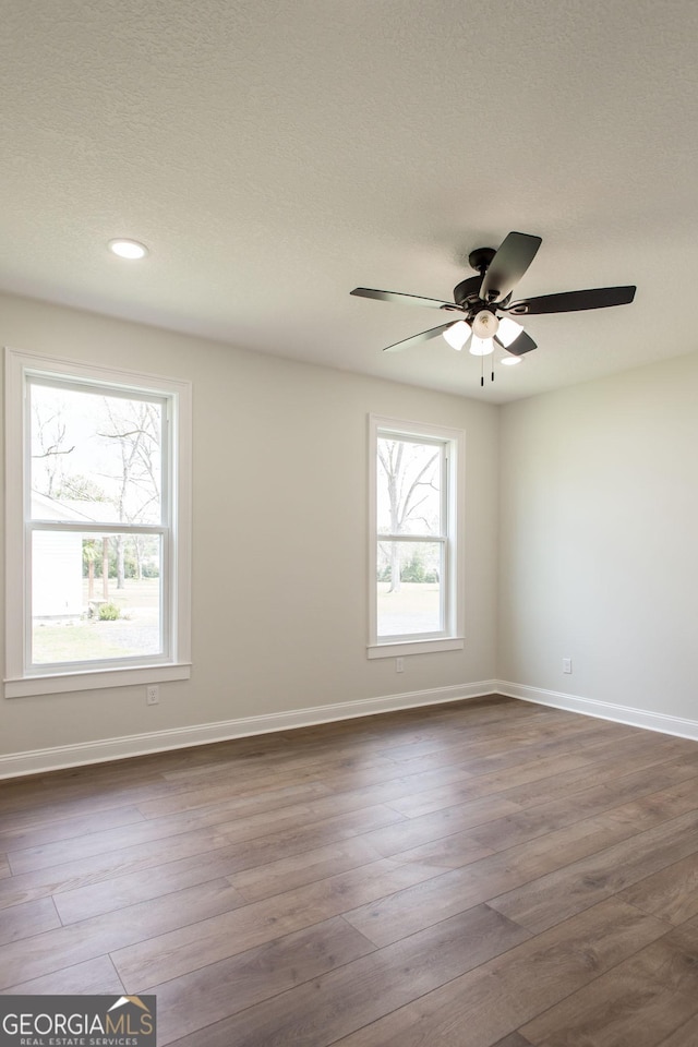 empty room with baseboards, dark wood-style floors, recessed lighting, a ceiling fan, and a textured ceiling
