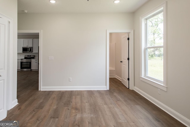 spare room with wood finished floors, plenty of natural light, baseboards, and recessed lighting