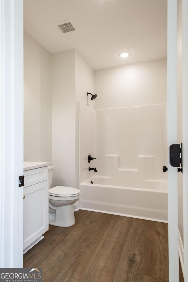 bathroom with wood finished floors, toilet, shower / bath combination, and vanity