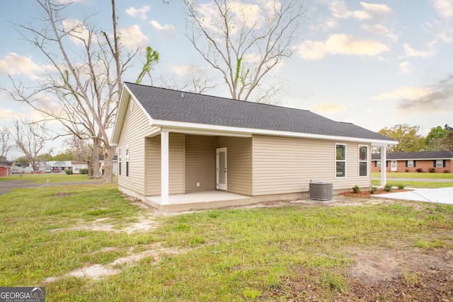 rear view of house featuring a patio, a lawn, and central AC