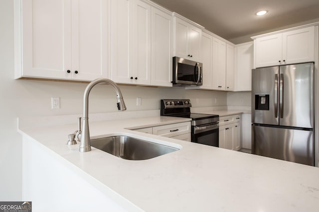 kitchen with appliances with stainless steel finishes, a sink, recessed lighting, and white cabinetry