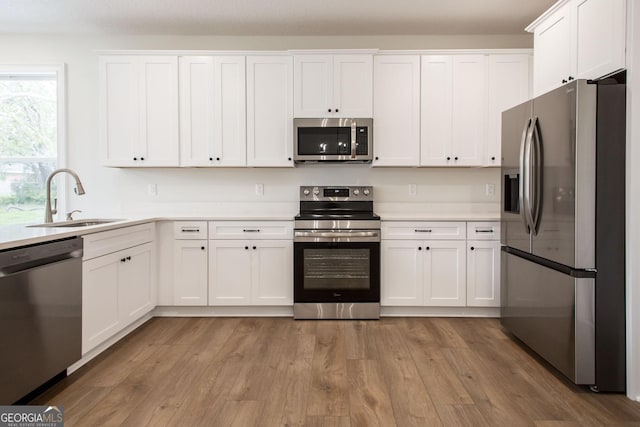 kitchen featuring appliances with stainless steel finishes, a sink, white cabinetry, and light countertops
