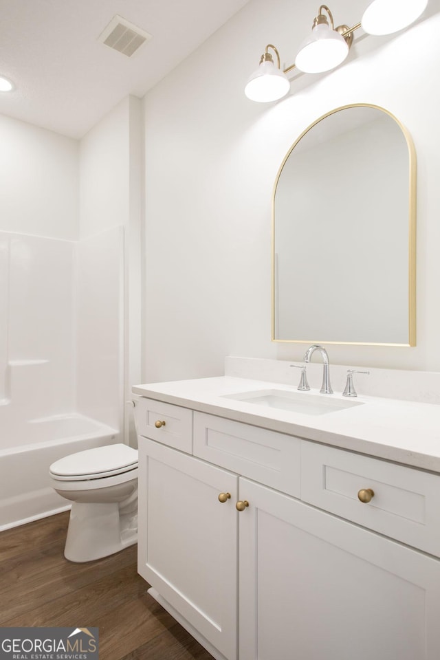 bathroom with wood finished floors, vanity, toilet, and shower / bath combination