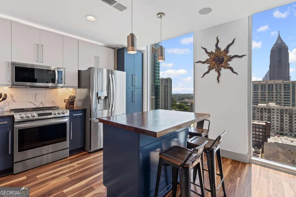 860 Peachtree St NE Unit 1712, Atlanta, GA 30308 - kitchen with appliances with stainless steel finishes, butcher block counters, a breakfast bar area, expansive windows, and backsplash