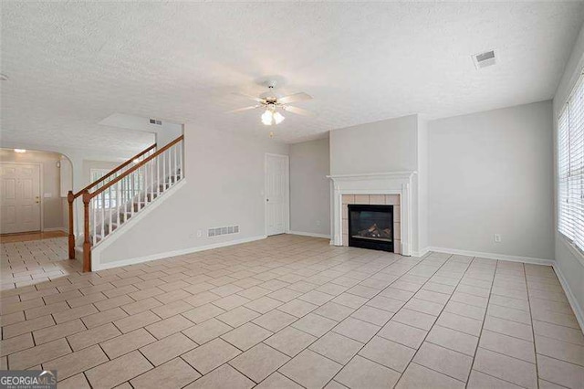 unfurnished living room with a textured ceiling, a ceiling fan, stairs, light tile patterned floors, and baseboards