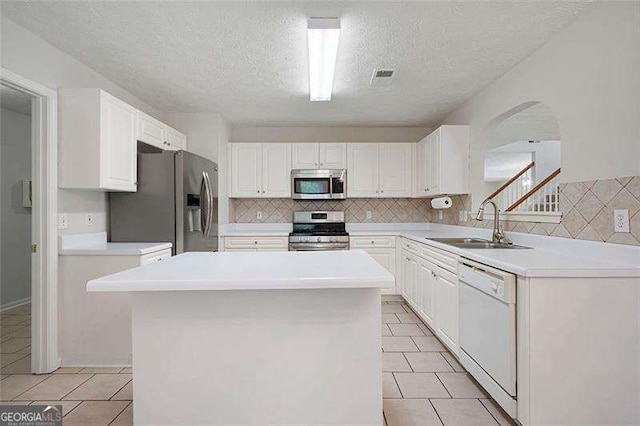kitchen with stainless steel appliances, a sink, arched walkways, light tile patterned flooring, and white cabinetry