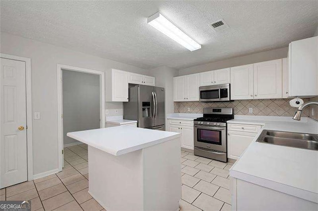 kitchen featuring stainless steel appliances, a sink, light tile patterned floors, white cabinetry, and a textured ceiling