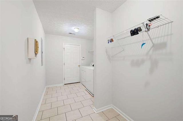 laundry room with washing machine and clothes dryer, a textured ceiling, baseboards, and light tile patterned floors