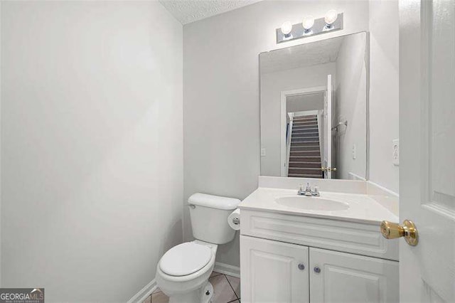 bathroom featuring toilet, vanity, tile patterned floors, a textured ceiling, and baseboards