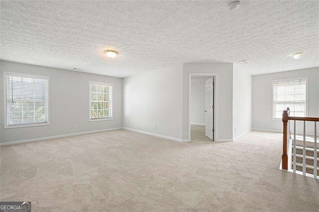 carpeted empty room featuring baseboards and a textured ceiling