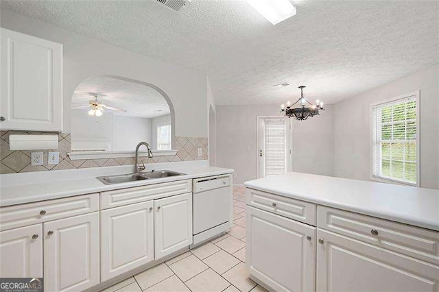 kitchen featuring dishwasher, a sink, arched walkways, decorative backsplash, and light countertops