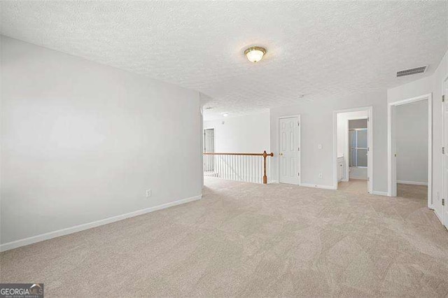 empty room featuring carpet floors, a textured ceiling, and baseboards