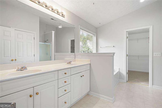 bathroom featuring double vanity, a shower stall, lofted ceiling, a textured ceiling, and a garden tub