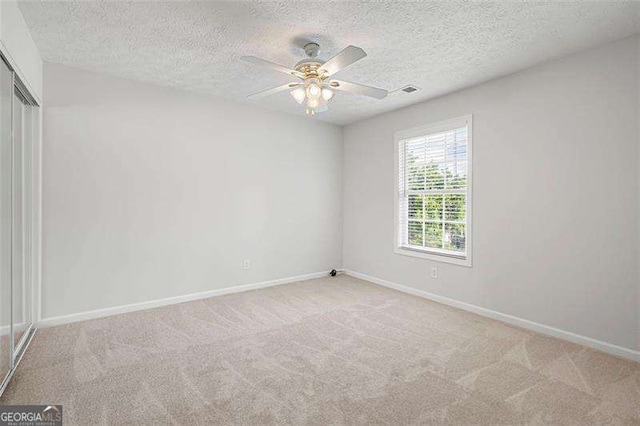 carpeted spare room with a textured ceiling, baseboards, and ceiling fan