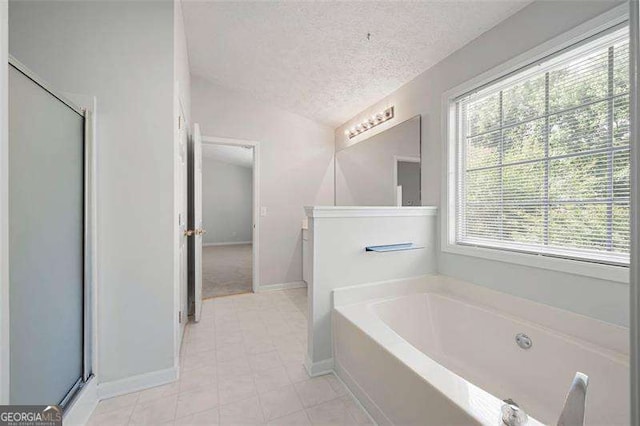 bathroom featuring a textured ceiling, baseboards, a bath, tile patterned floors, and a shower stall