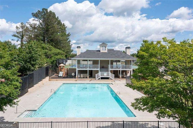 community pool featuring fence, stairs, and a patio