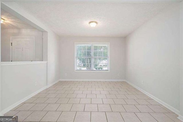 spare room featuring a textured ceiling and baseboards
