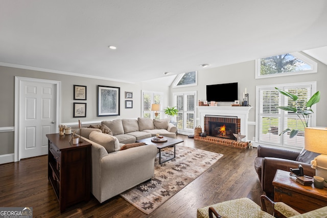 living area with a brick fireplace, healthy amount of natural light, dark wood-type flooring, vaulted ceiling, and crown molding