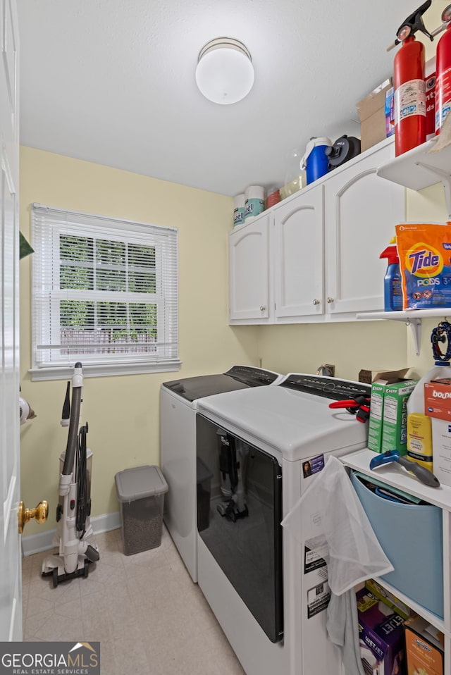 washroom with washer and clothes dryer, cabinet space, light tile patterned floors, and baseboards