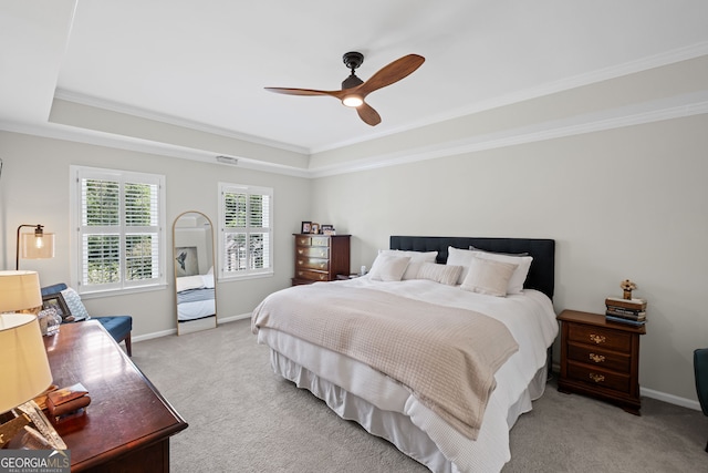 bedroom with light colored carpet, a tray ceiling, ornamental molding, baseboards, and a ceiling fan