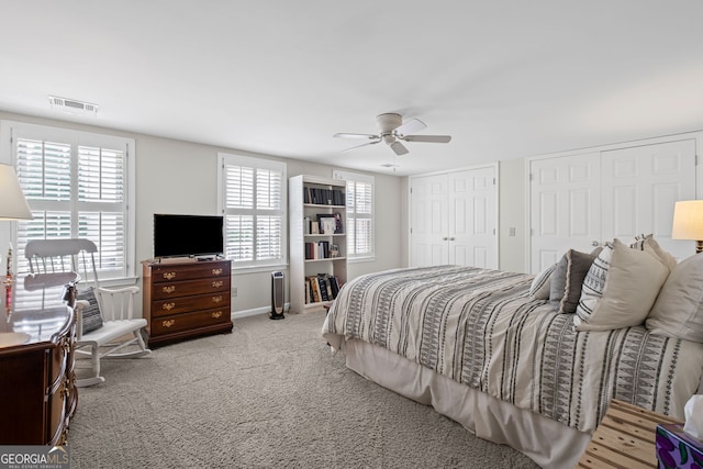 carpeted bedroom with multiple closets, multiple windows, baseboards, and a ceiling fan
