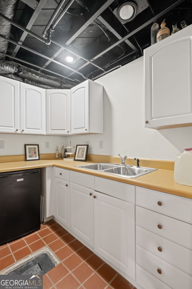 kitchen featuring a sink, white cabinetry, light tile patterned flooring, light countertops, and fridge
