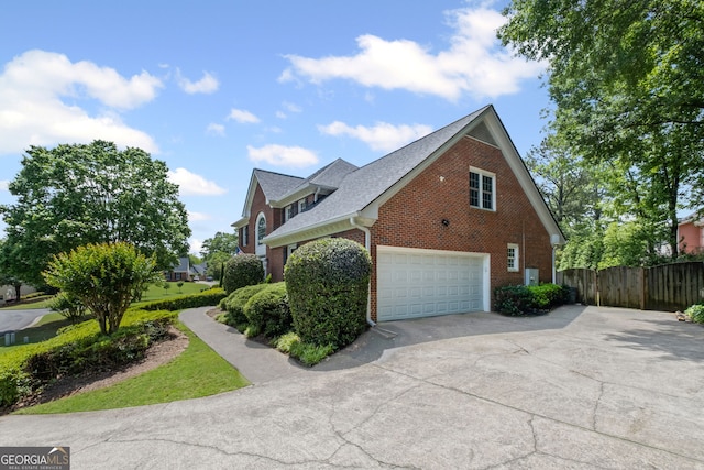 view of side of home featuring brick siding, an attached garage, concrete driveway, fence, and roof with shingles