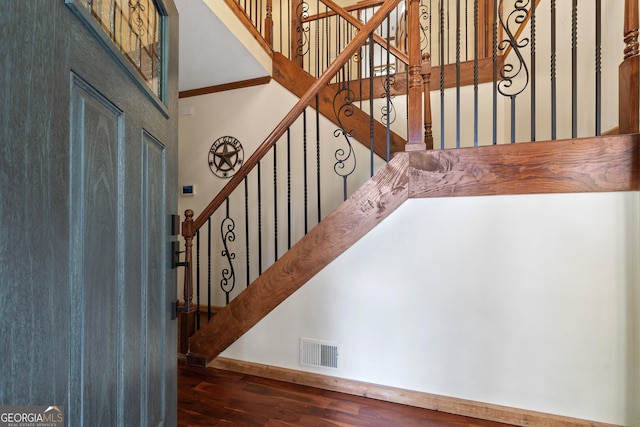 stairs with wood finished floors, ornamental molding, and baseboards