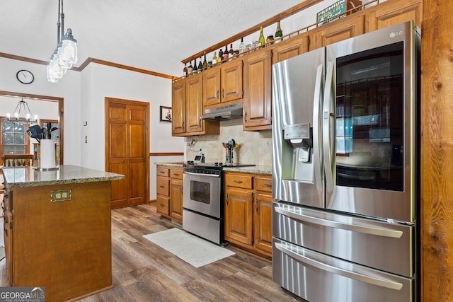 kitchen featuring appliances with stainless steel finishes, crown molding, a chandelier, under cabinet range hood, and dark wood finished floors