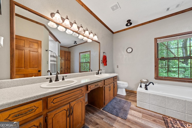 full bathroom featuring ornamental molding, wood finished floors, double vanity, toilet, and a bath